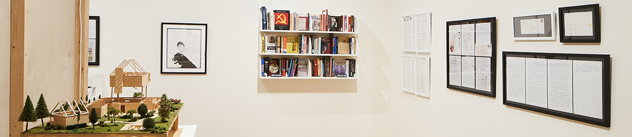 view of gallery with a wooden model of a house, several letters and drawings, and a bookshelf with books